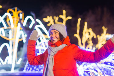 Midsection of woman standing in illuminated park during winter