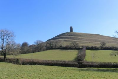 Scenic view of grassy landscape against clear blue sky