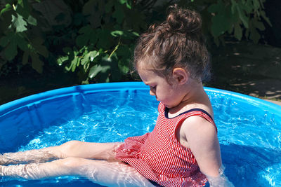 Cute toddler playing in the water basin in the backyard