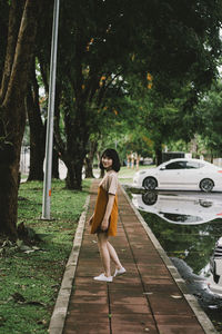 Side view portrait of young woman standing on footpath