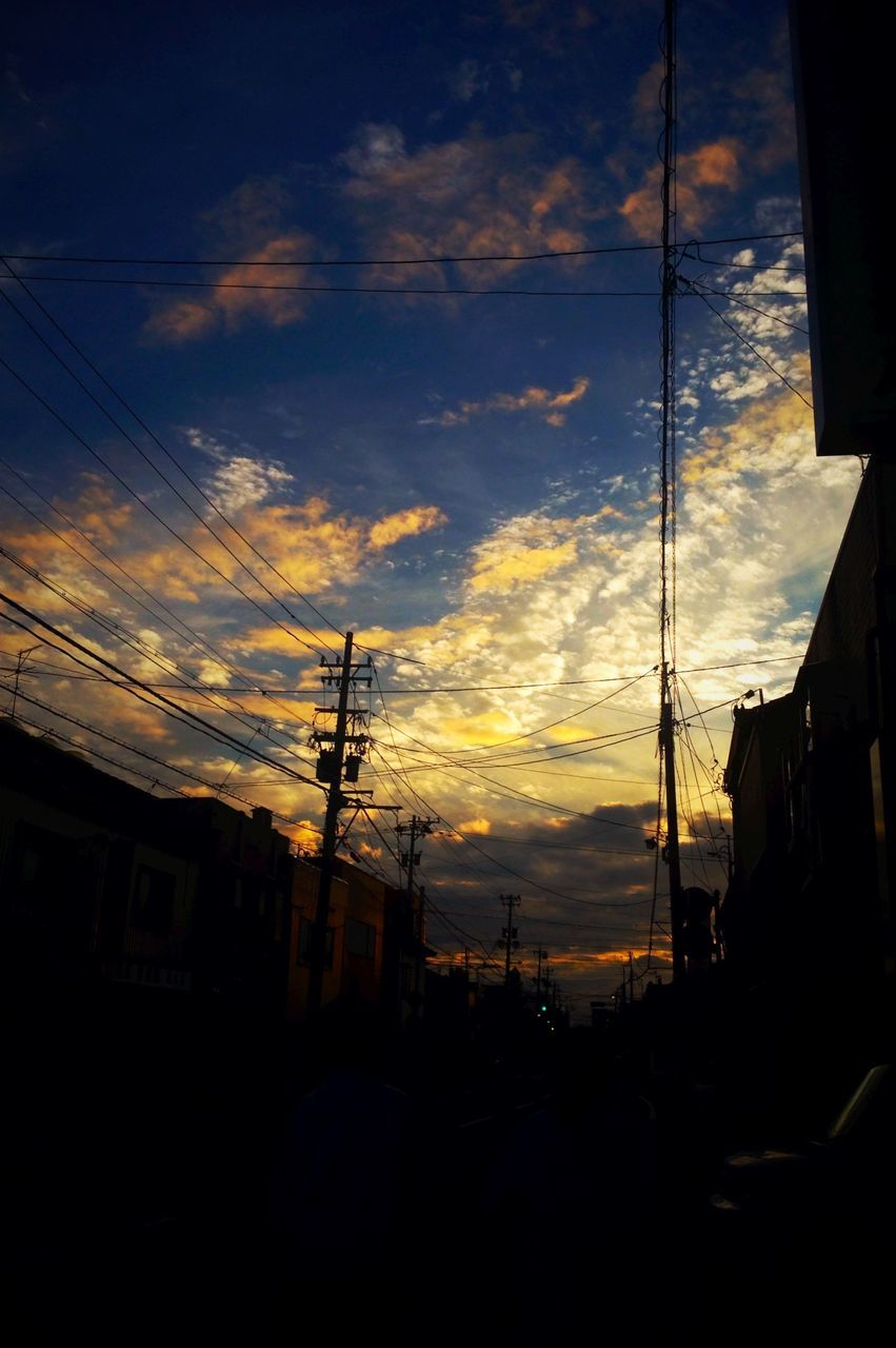 power line, electricity pylon, building exterior, sunset, sky, electricity, power supply, built structure, architecture, cable, silhouette, cloud - sky, city, residential structure, power cable, fuel and power generation, cloud, house, connection, residential building