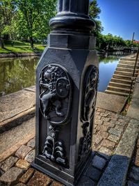 Close-up of metal railing on footpath by lake