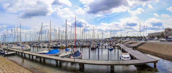 Sailboats moored in harbor against sky