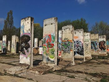 Graffiti on wall by trees against sky