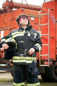 Firefighter looking away while standing by fire engine