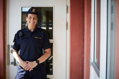 Portrait of smiling policewoman standing outside police station