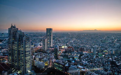 High angle view of city lit up at sunset