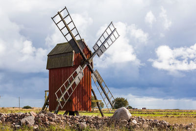 Traditional windmill on field against cloudy sky