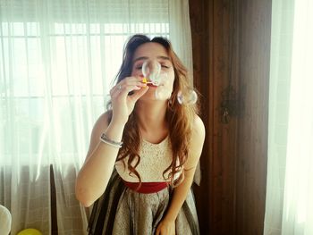 Portrait of young woman eating while standing at home