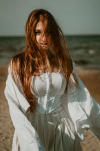 Portrait of young woman standing against sea