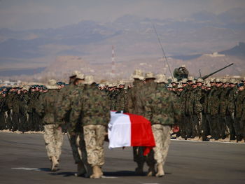 Army soldiers with coffin on road against mountains