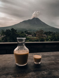 Coffee on table by mountains against sky