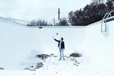 Full length of man skateboarding on snow against sky