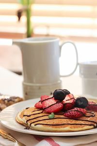 Close-up of fruits on pancake in plate at table