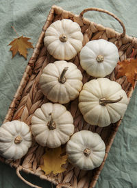 White pumpkins and autumn leaves on a wicker tray. autumn home decor.
