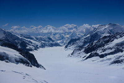 Scenic view of snowcapped mountains against blue sky