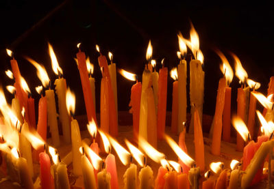 Close-up of lit candles in temple at night