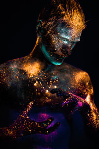 Close-up of shirtless male model with powder paint against black background