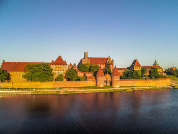 Buildings at waterfront against clear sky