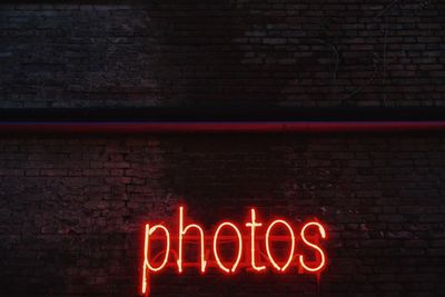 Illuminated neon photos text on brick wall