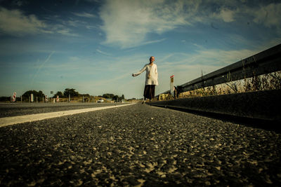 Man standing on road in city against sky