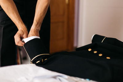 Cropped hand of man adjusting suit at home