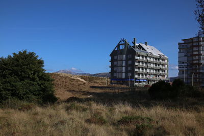 House on field against clear blue sky