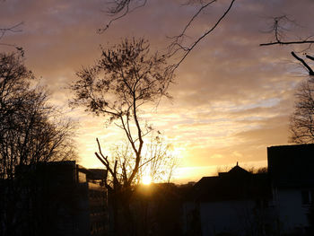 Silhouette of buildings against cloudy sky at sunset