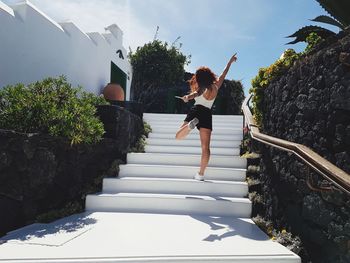 Woman walking on staircase against sky