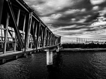 Bridge over river against cloudy sky