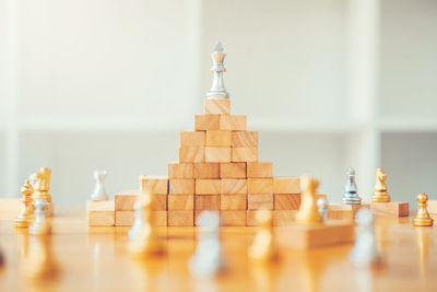 Wooden blocks and chess pieces on table against wall