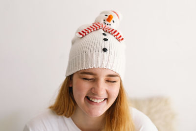 Funny young girl in a christmas hat with a snowman and a red scarf.