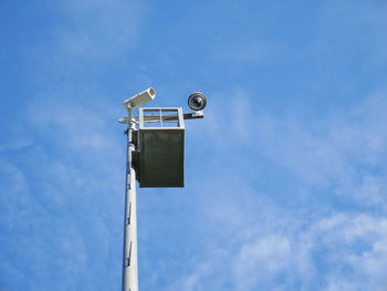 Low angle view of security camera on pole against sky during sunny day