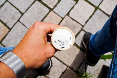 Cropped image of hand holding ice cream cone on paved footpath