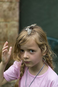 Portrait of cute girl with butterfly in hair outdoors