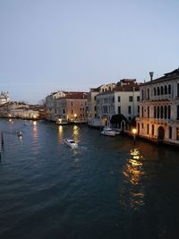 Canal amidst buildings in city against clear sky