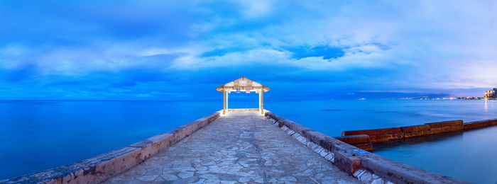Pier over sea against blue sky