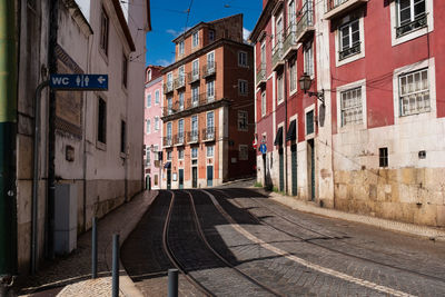Narrow street in lisbon portugal with tram tracks, public toilet on the side