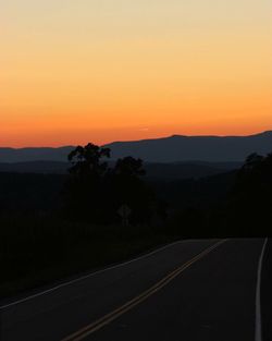 Road passing through landscape during sunset