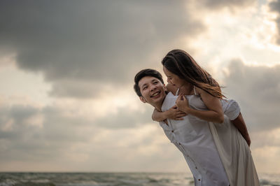 Low angle view of couple on beach against sky