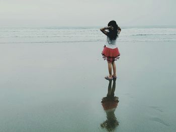 Full length rear view of girl standing on beach