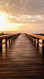 Wooden pier on bridge against sky during sunset