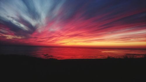 Scenic view of sea against dramatic sky during sunset
