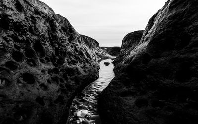 Swan on rock formation against sky