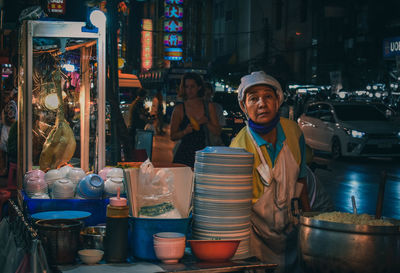 People standing at market stall in city at night