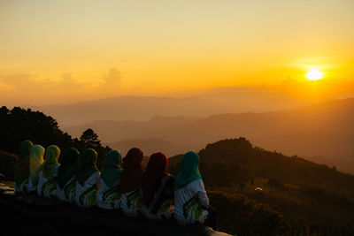 People sitting on mountain during sunset