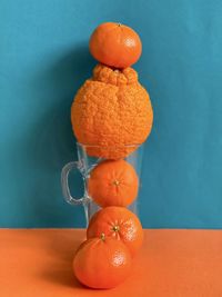 Close-up of orange fruits on table against wall