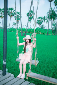 Woman sitting on grass against trees