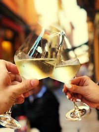 Close-up of cropped hands toasting wineglasses at sidewalk cafe