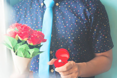 Midsection of woman holding red flowering plant